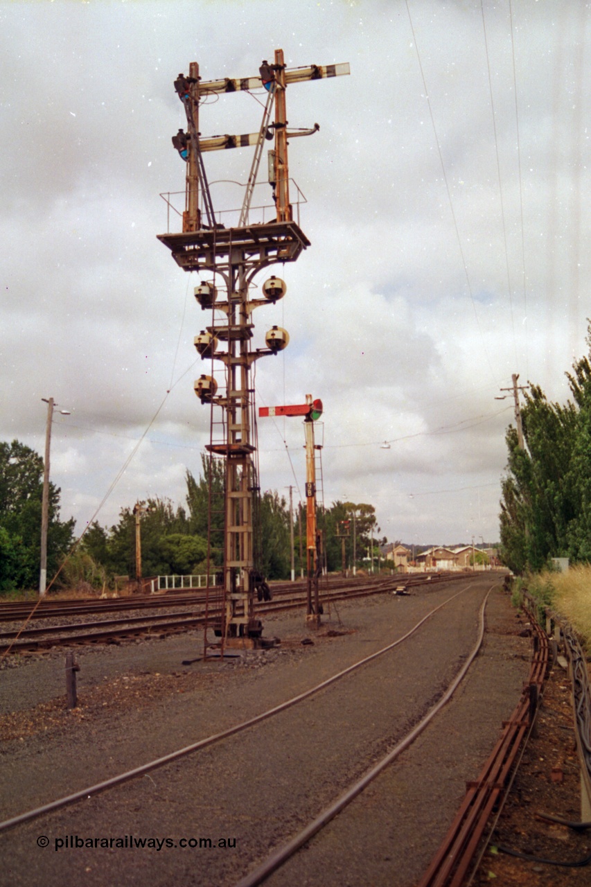 139-07
Ballarat yard, looking east, rear view of semaphore and disc signal post 11, semaphore signal post 9B facing the camera, Ballarat East signal box and goods shed visible in the background.
