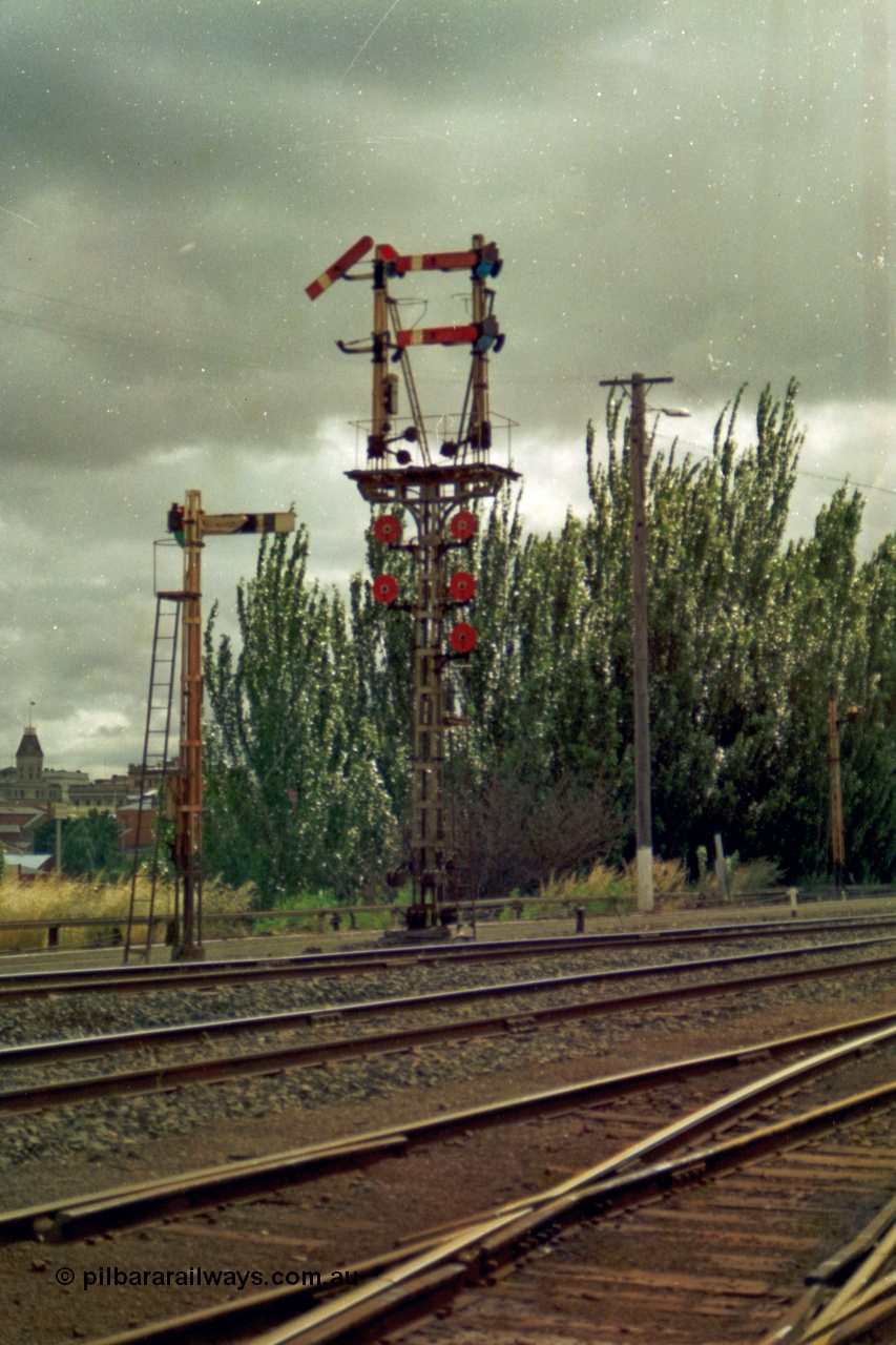 139-11
Ballarat yard, semaphore and disc signal Post 11 with rear facing semaphore signal post 9B, the top left hand Arm is the Down Home to Post 21 for No. 1 Road and is pulled off for an arriving passenger train. Top right hard Arm is the Down Home to Post 23 for No. 3 Road, bottom right Arm Down Home to Post 20 for No. 4 Road. Discs are all From 'U', top left to Car Sidings, centre left Disc towards Post 21 for No. 1 Road, bottom left Disc towards Post 22 for No. 2 Road, top right Disc towards Post 23 for No. 3 Road, centre right Disc towards Post 20 for No. 4 Road and the right bottom Disc to No. 5, 6 or 7 Roads.
