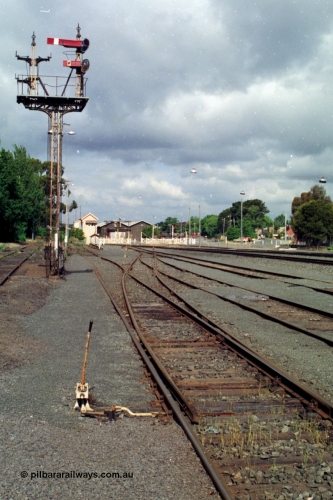 139-10
Ballarat yard, semaphore signal Post 7 controlled from Ballarat East Signal Box, which can be seen in the background, image taken from point 'Y', goods arrival and departure roads at right with passenger lines at far right. This reduced signal post now only contains the Up Home Up Passenger Line to No. 1 Road to Post 4 at Ballarat East platform and the Calling On Up Passenger Line to No. 1 Road. The stripped left hand mast was for movements from the Goods Departure Road and the Goods Sidings.
