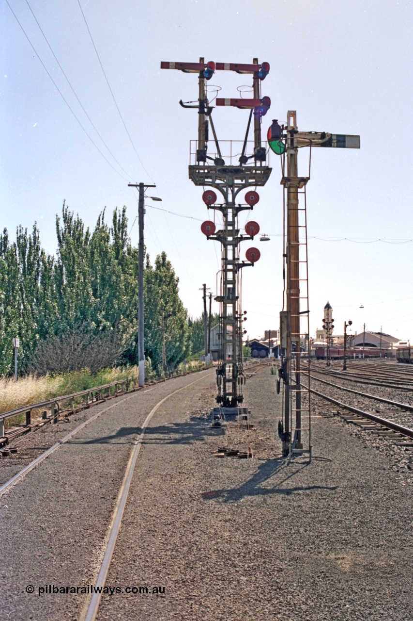 140-1-07
Ballarat station yard overview, combination semaphore and disc signal post 11 facing the camera and semaphore signal post 10 looking toward the station, Ballarat signal box A behind post 11, station clock tower and platform canopy on the right.
