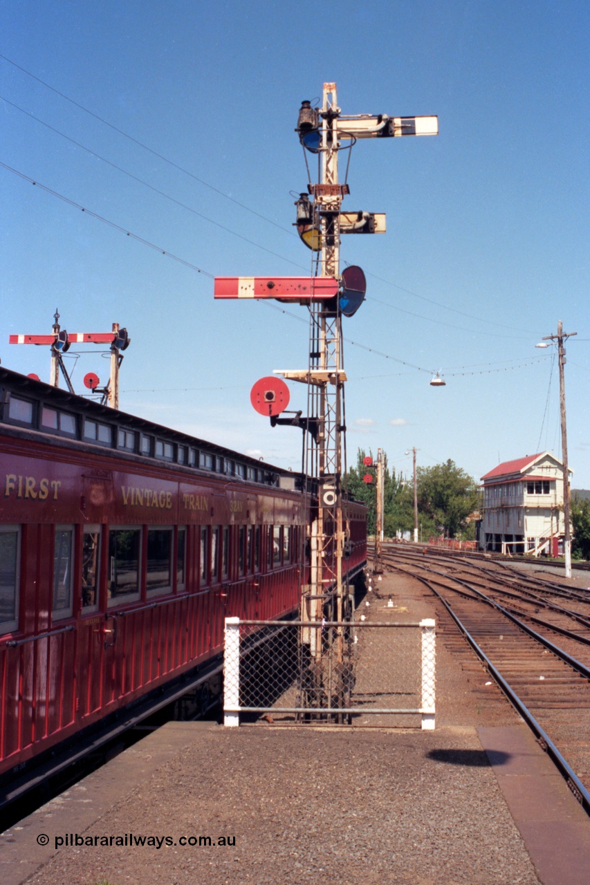 140-1-12
Ballarat station platform 2 looking towards Ballarat signal box A, semaphore signal post 20, the facing semaphore is the up home signal to the up passenger line and the disc is for the goods departure or Siding Y, the two semaphores facing away are the down home for No.4 Rd (platform road) and the calling on for No.4 Rd, double disc signal post 17 in the distance, quad disc signal post 16 on the right and the top of semaphore signal post 19 is visible over the passenger carriage.
