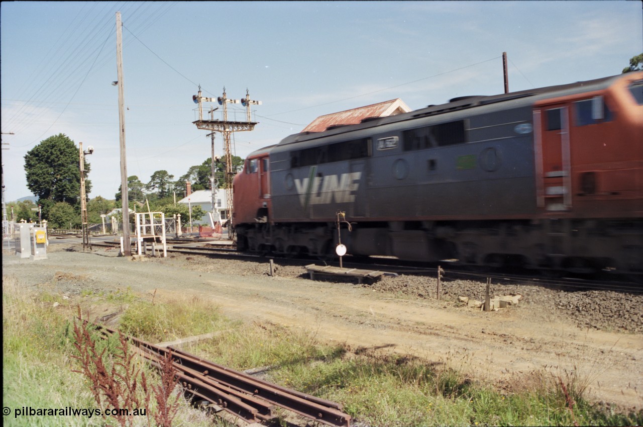 140-2-01
Ballarat, Linton Junction Signal Box, or Ballarat D, broad gauge V/Line A class locomotive A 62 Clyde Engineering EMD model AAT22C-2R serial 84-1183 rebuilt from B 62 Clyde Engineering EMD model ML2 serial ML2-3 races through Linton Junction with an up passenger train, and surrenders the electric staff on 'the auto' disc signal 21, interlocked gates for the Gillies Street grade crossing and triple doll semaphore signal post 20.
Keywords: A-class;A62;Clyde-Engineering-Rosewater-SA;EMD;AAT22C-2R;84-1183;rebuild;bulldog;