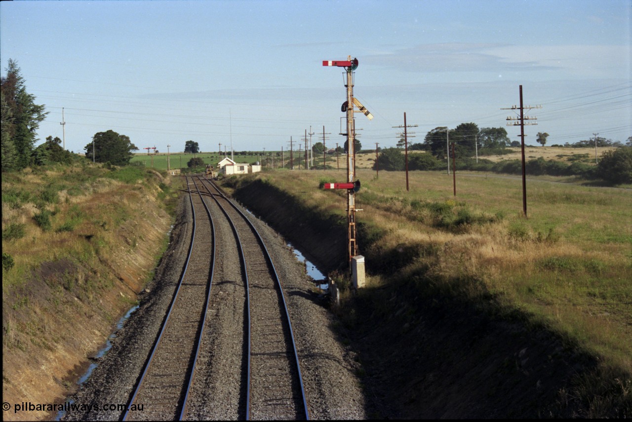 140-2-09
Warrenheip, station overview looking south, Melbourne line curves to the left and the Geelong line to the right, the Tamper track machine is in Siding A, the points and crossing lead to Siding B, signal box, staff exchange platform, notice how high the semaphore signal posts are.
