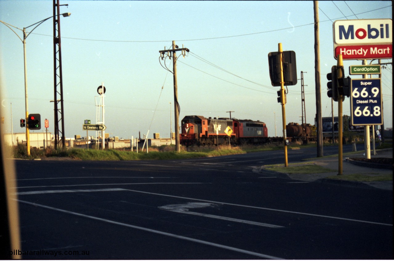 141-1-15
Sunshine, Wright Street / Sunshine Road grade crossing, 66 cents a litre for fuel?? Must have been 1992, and broad gauge V/Line X class and S class with the down Corio - Wodonga oil (fuel) train.
Keywords: X-class;Clyde-Engineering-Granville-NSW;EMD;G26C;