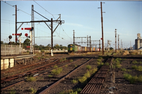 141-1-03
Sunshine, broad gauge down Adelaide goods train behind Australian National BL class and a V/Line G class cross over the passenger lines from the Independent Through Lines heading for No.3 road and the main western line, station platform, semaphore and disc signal posts, points, point rodding, looking east, Newport Loop Line on the right.
Keywords: BL-class;BL33;Clyde-Engineering-Rosewater-SA;EMD;JT26C-2SS;83-1017;
