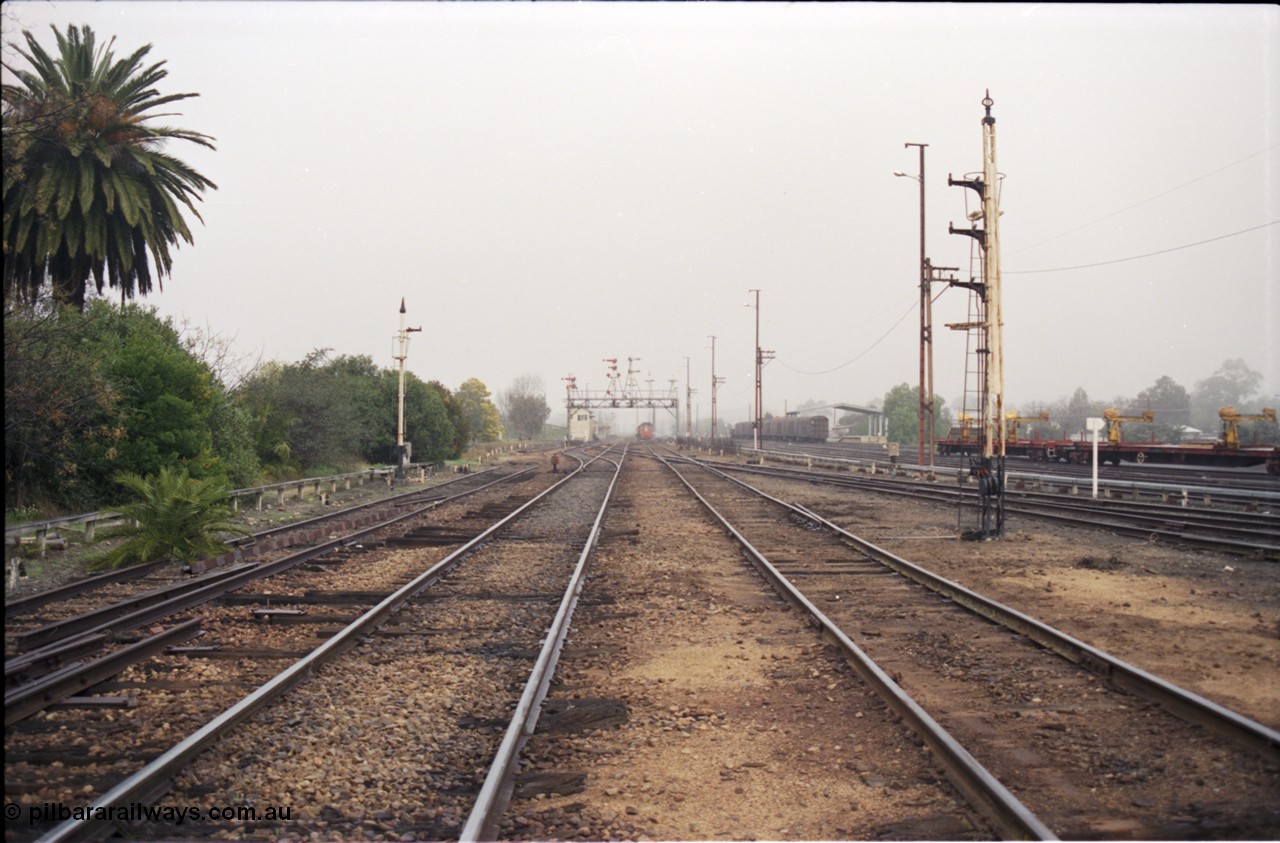 142-1-18
Benalla station yard overview looking south, disc signal posts 31 on the left and 32 on the right stripped, Siding Z at left, crossovers removed, Benalla B signal box and 9303 stabled goods in the background, rail recovery rake at right.
