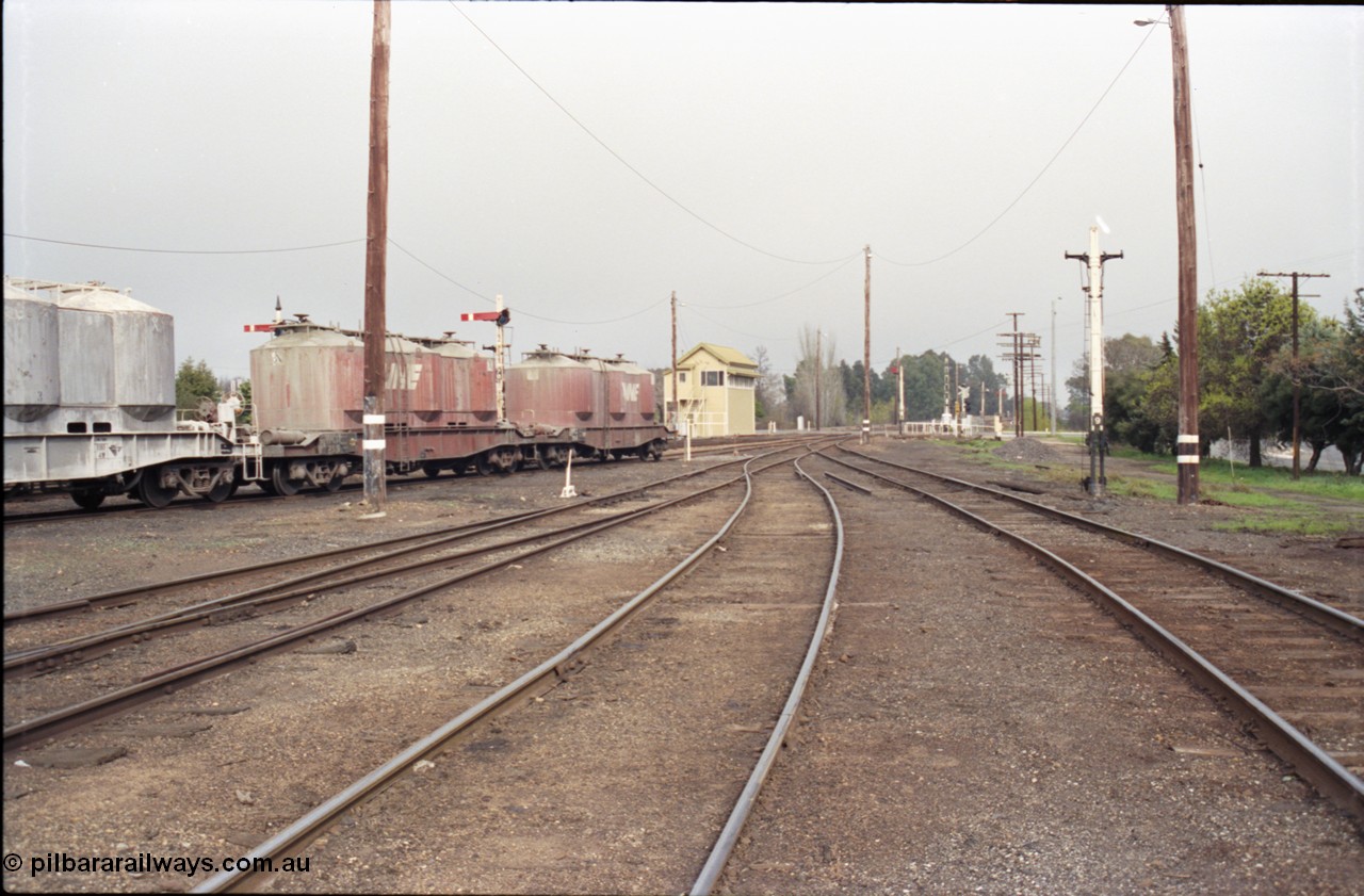 142-1-35
Benalla yard overview looking south from goods yard, No. 4, 5, and 6 Roads end with goods yard road on the right, remains of Siding B can be seen beyond stripped disc signal post 9, semaphore signal posts 7 and 7B are visible behind the VPCX class waggons, Benalla A signal box and disc signal 
