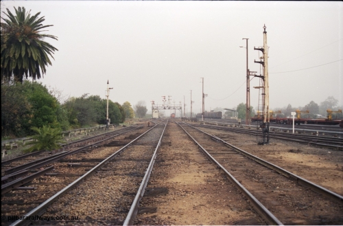 142-1-18
Benalla station yard overview looking south, disc signal posts 31 on the left and 32 on the right stripped, Siding Z at left, crossovers removed, Benalla B signal box and 9303 stabled goods in the background, rail recovery rake at right.
