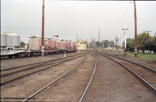 142-1-35
Benalla yard overview looking south from goods yard, No. 4, 5, and 6 Roads end with goods yard road on the right, remains of Siding B can be seen beyond stripped disc signal post 9, semaphore signal posts 7 and 7B are visible behind the VPCX class waggons, Benalla A signal box and disc signal 
