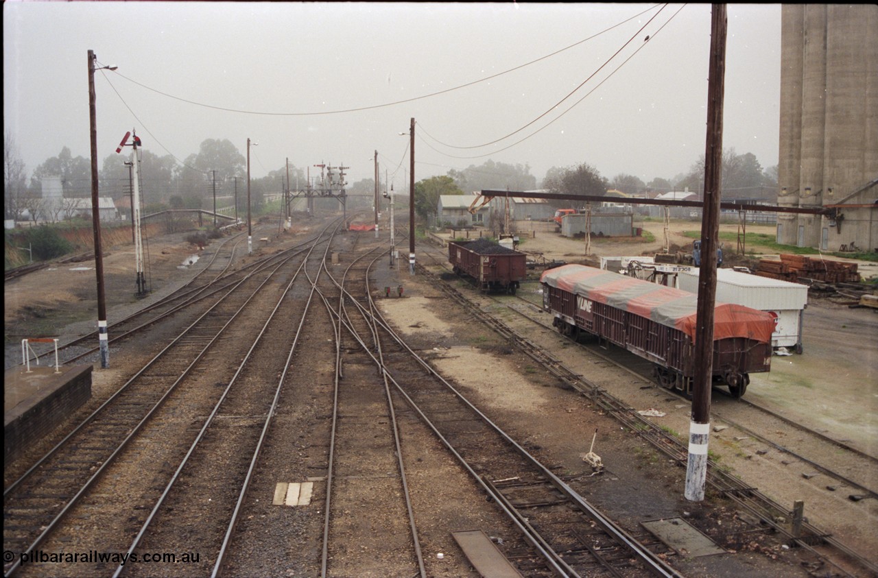 142-2-02
Wangaratta station yard overview looking south from footbridge, semaphore signal post 12 pulled off for up train, fuel siding is visible on the left, standard gauge line is in the cutting at far left, signal gantry in the distance, V/Line VOCX and VOFX type bogie open waggons at right.
Keywords: VOCX-type;VOFX-type;