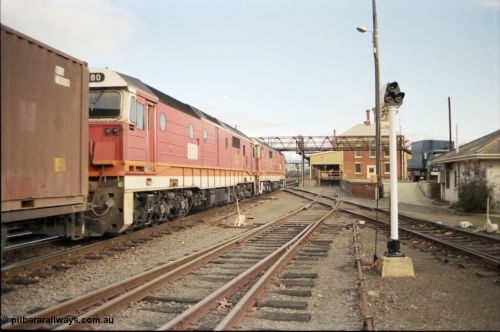 142-3-01
Albury station yard, standard gauge NSWSRA candy liveried 81 class locos 8156 Clyde Engineering EMD model JT26C-2SS serial 84-1075 and 8180 serial 85-1099 pull into the platform with a Melbourne bound goods where they will cut off. The diamond and colour light signal in this view are for the V/Line broad gauge track that is used for fuel waggons.
Keywords: 81-class;8156;Clyde-Engineering-Kelso-NSW;EMD;JT26C-2SS;84-1075;