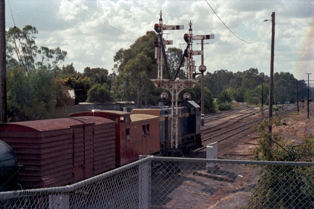 143-09
Wangaratta, down Wahgunyah Special 'Stringybark Express' departs up home semaphore past signal Post 23 with broad gauge VR liveried Y class Y 133 Clyde Engineering EMD model G6B serial 65-399, leading ZL type six wheel guards van ZL 2, U type four wheel louvre van U 892 and WT type four wheel water tank WT 236, sidings in the background are extensions of 3, 4 and 5 Roads, the Rowan Street underpass is visible beyond along with the Ovens River bridge.
