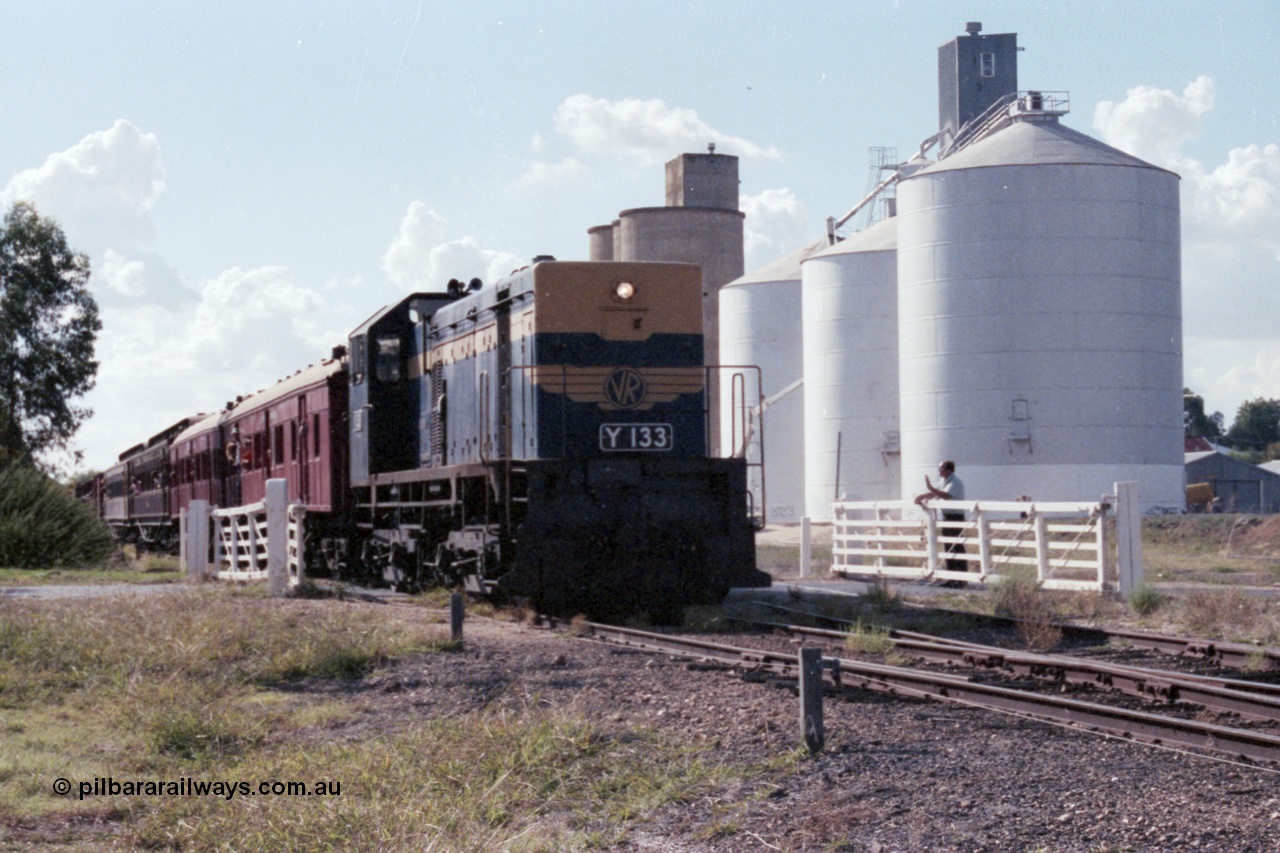 143-36
Rutherglen, up Wahgunyah 'Stringybark Express' mixed special under the power of VR liveried broad gauge Y class Y 133 Clyde Engineering EMD model G6B serial 65-399 crosses Howlong St through the non-interlocked hand swing gates as the Williamstown and Ascom style silos stand sentinel and the signaller gives a wave.
Keywords: Y-class;Y133;Clyde-Engineering-Granville-NSW;EMD;G6B;65-399;