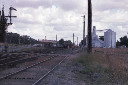 143-12
Springhurst station yard overview with semaphore signal Post 4 pulled for the Wahgunyah line as broad gauge VR liveried Y class Y 133 Clyde Engineering EMD model G6B serial 65-399 slows to exchange the electric staff for the ordinary staff with the down broad gauge 'Stringybark Express' mixed special, station building with signaller at staff exchange platform, Murphy silo complex and Victorian Oats Pool shed on the right.
