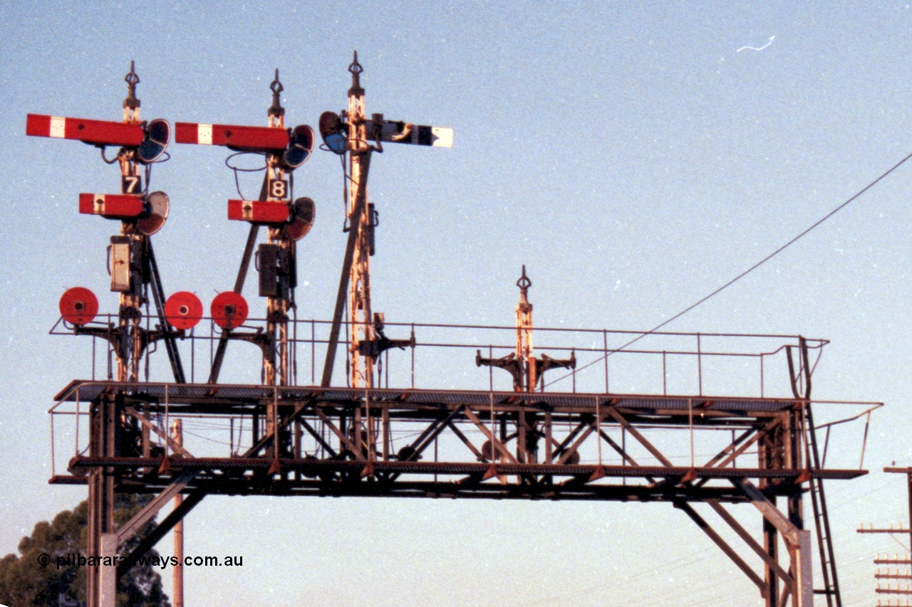 144-11
Wangaratta, signal gantry with semaphore and disc signal Posts 7, 8, 9 and stripped disc Post 10. Post 7 top arm Home Signal 'A' to No. 2 Road to Post 17, bottom arm Calling-on Signal from 'A' to No. 2 Rd towards Post 17, left hand Disc 'A' to No. 4 or 5 Roads towards Post 17; or to No. 6 Rd, right hand Disc 'A' to No. 3 Rd towards Post 17. Post 8 top arm Home Signal 'A' to No. 1 Rd towards Post 20, bottom arm Calling-on Signal 'A' to Main Line to Post 1, Disc 'A' to Carriage Dock. Post 9 arm Up Home Signal 'A' to Main Line to Post 1, removed Disc was for access to cattle sidings. And stripped Disc Post 10 was for movements from Siding F to No. 1 Rd or the the Carriage Dock.
