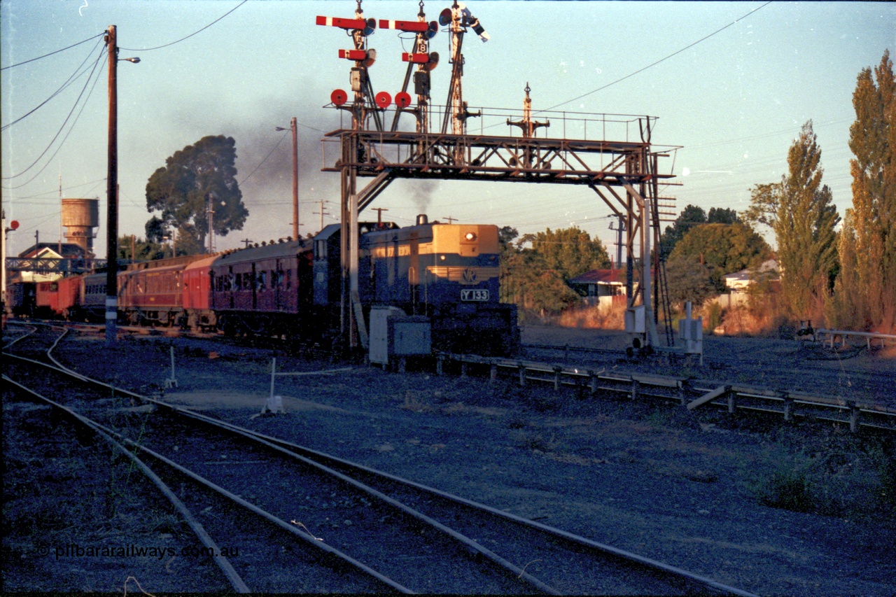 144-14
Wangaratta station yard view, VR liveried broad gauge Y class Y 133 Clyde Engineering EMD model G6B serial 65-399 leads the Wahgunyah 'Stringybark Express' mixed special south bound for Benalla under the signal gantry with semaphore signal Post 9 arm Up Home Signal 'A' to Main Line to Post 1 pulled off for the move.
Keywords: Y-class;Y133;Clyde-Engineering-Granville-NSW;EMD;G6B;65-399;