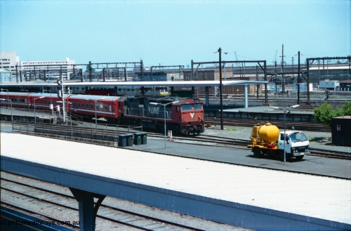 145-03
Spencer Street Station overview, broad gauge V/Line N class N 454 'City of Horsham' Clyde Engineering EMD model JT22HC-2 serial 85-1222 departs with a carriage set, a suburban Met coloured Comeng spark in the background, septic tank pump truck in foreground.
Keywords: N-class;N454;Clyde-Engineering-Somerton-Victoria;EMD;JT22HC-2;85-1222;