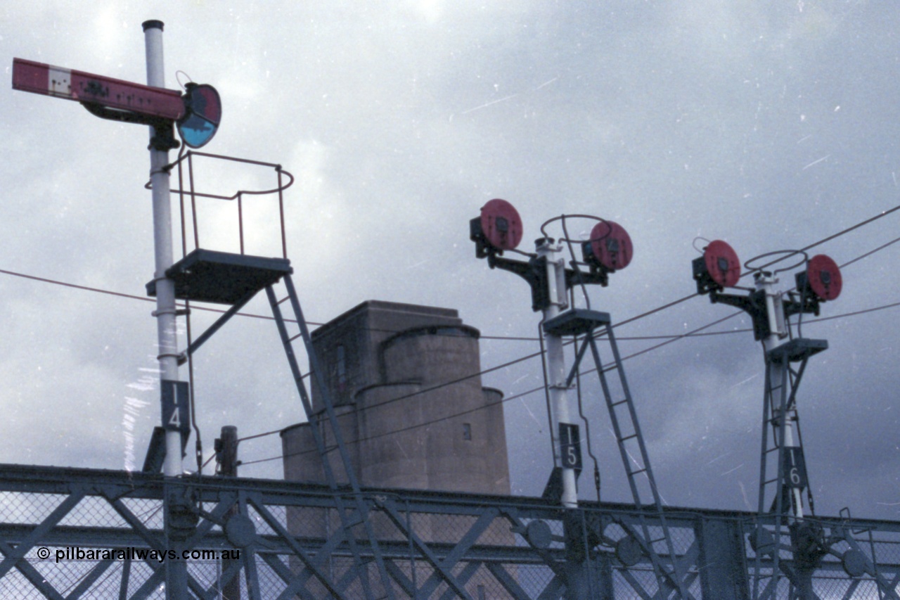 148-11
Wangaratta, signal gantry on foot bridge with semaphore signal post 14 and twin disc signal posts 15 and 16. Post 14 is the Up Home Signal from No.2 Road to 'A' to Post 9. Post 15 are both Up Signals, Left-hand Disc from No. 3 Road to 'A' towards Post 9, Right-hand Disc from No. 3 Road to Sidings 'H' or 'E'. Post 16 are both Up Signals, Left-hand Disc from Nos. 4, 5 or 6 Roads to 'A' towards Post 9, Right-hand Disc from Nos. 4, 5 or 6 Roads to Sidings 'H' or 'E'.
