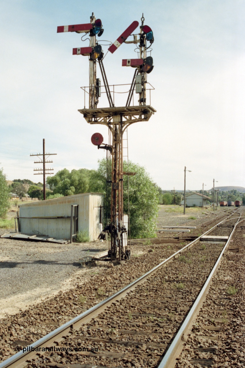 149-11
Bacchus Marsh down home signal post 2, with the signal pulled off for No.1 Rd or the platform road for a down Ballarat passenger train, gangers trolley shed is behind post and goods shed and stabled passenger sets in the background.
