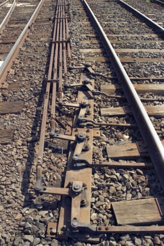 149-14
Bacchus Marsh, track view of point rodding changing track sides under rails with pivots.

