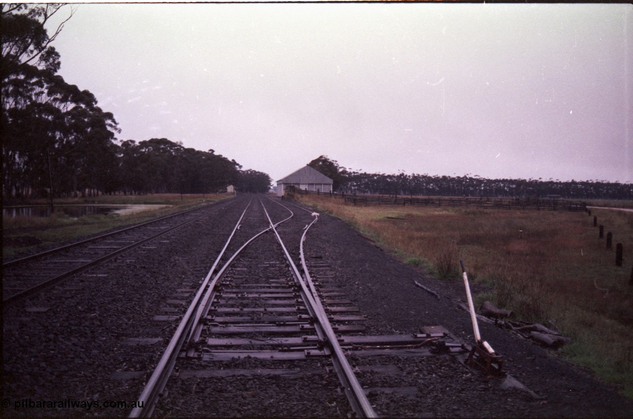 150-20
Lismore station yard overview from Maroona end of goods loop looking east, station building at left on No. 1 road, taken from goods loop points on No.2 road, point lever, stock yards and races with grain bunker behind.
