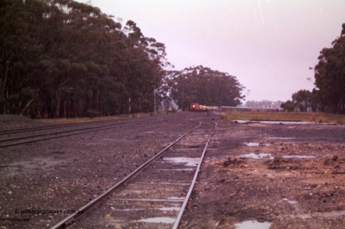 150-14
Lismore, station yard overview looking towards Melbourne from goods loading ramp, V/Line broad gauge C classes Clyde Engineering EMD model GT26C leading Adelaide bound goods train 9169 at the trailable points which are set for left hand lay.
