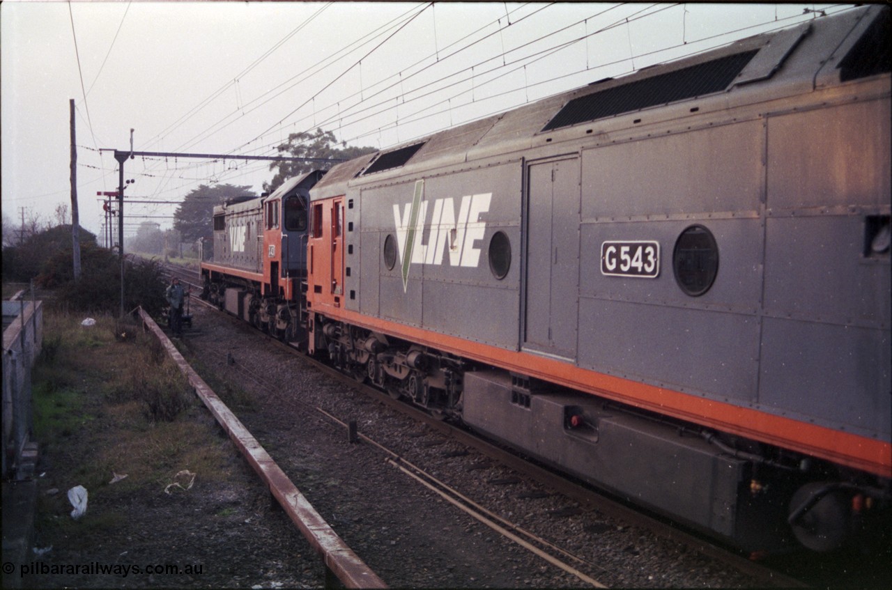 152-03
Morwell, ground frame and signal post 8 disc pulled off for Briquette Sidings, signaller at auxiliary frame waving, V/line broad gauge light engines X class X 43 Clyde Engineering EMD model G26C serial 70-706 and G class G 543 Clyde Engineering EMD model JT26C-2SS serial 89-1276 run on the down with train 9444, see images in Set 121-27, 28, 29 and 30.
Keywords: G-class;G543;Clyde-Engineering-Somerton-Victoria;EMD;JT26C-2SS;89-1276;