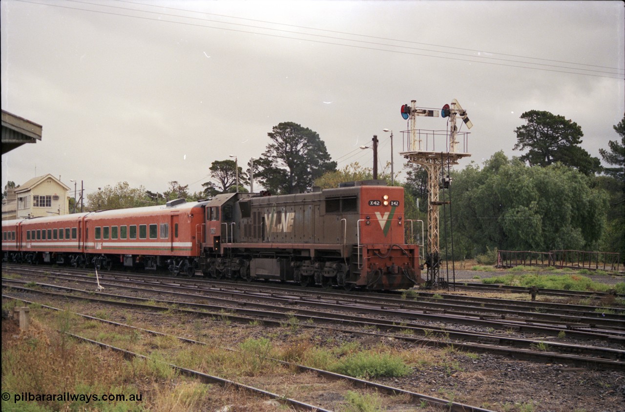 153-1-03
Bacchus Marsh yard view with V/Line broad gauge X class X 42 Clyde Engineering EMD model G26C serial 70-705 long end leading and N set on an up passenger train departing past signal post 5 pulled off for move from No. 1 road to mainline, turntable in background.
Keywords: X-class;X42;Clyde-Engineering-Granville-NSW;EMD;G26C;70-705;