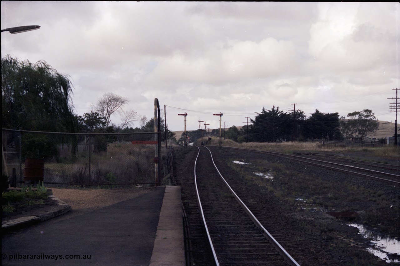 153-1-06
Ballan yard view looking towards Melbourne from station platform, semaphore signal posts 3 and 4 for up departure moves and semaphore signal post 2 down home, searchlight signal post 7? In the background, stand pipe at end of platform and stockyards at right.
