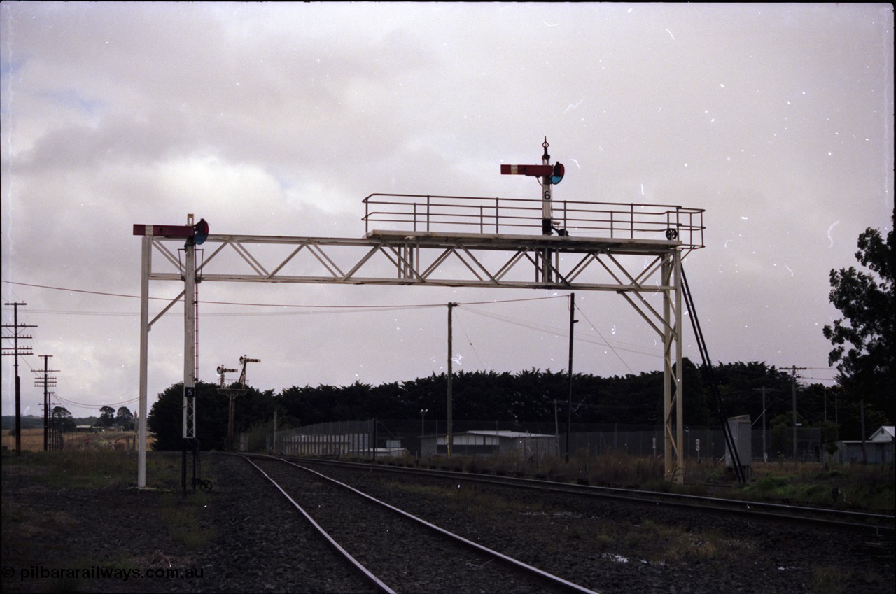 153-1-08
Ballan yard view looking towards Ballarat, signal gantry with semaphore post 6 for mainline moves, semaphore signal post 5 for the goods loop and semaphore signal post 7 up home, colour light signal post 10 in the distance.
