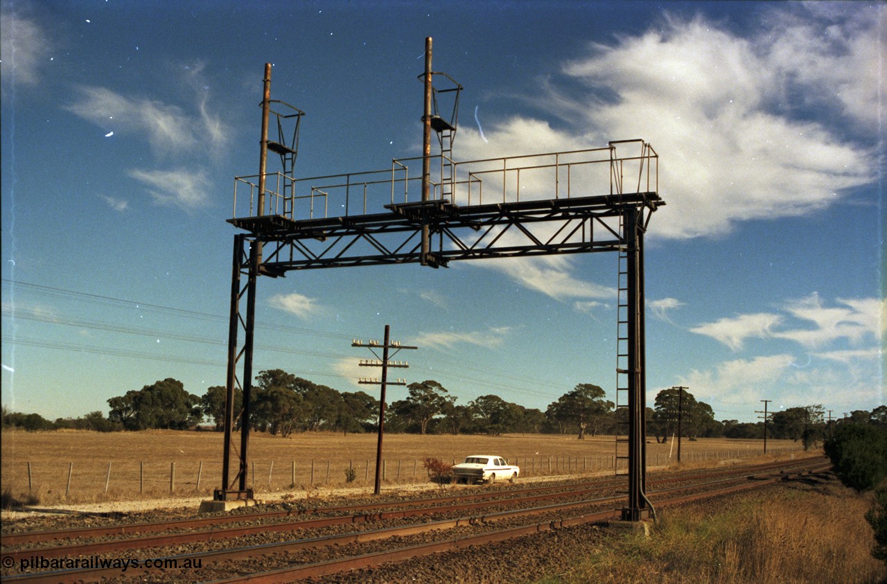 153-2-02
Bank Box Loop, broad gauge track view of redundant signal gantry following loop extension back in 1982, looking towards Ballarat, HK Holden framed under gantry.
