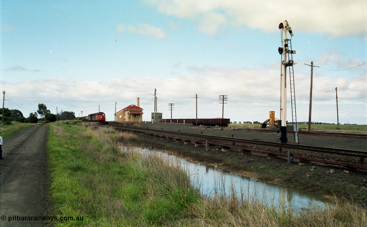 154-04
Gheringhap station yard overview, station building, shed, VOJF type bogie gypsum waggons, unloading contraption, semaphore signal pulled off for Maroona line, V/Line broad gauge goods train 9169 to Adelaide, via Cressy prepares to depart behind triple C class locomotives Clyde Engineering EMD model GT26C.
Keywords: C-class;C510;Clyde-Engineering-Rosewater-SA;EMD;GT26C;76-833;