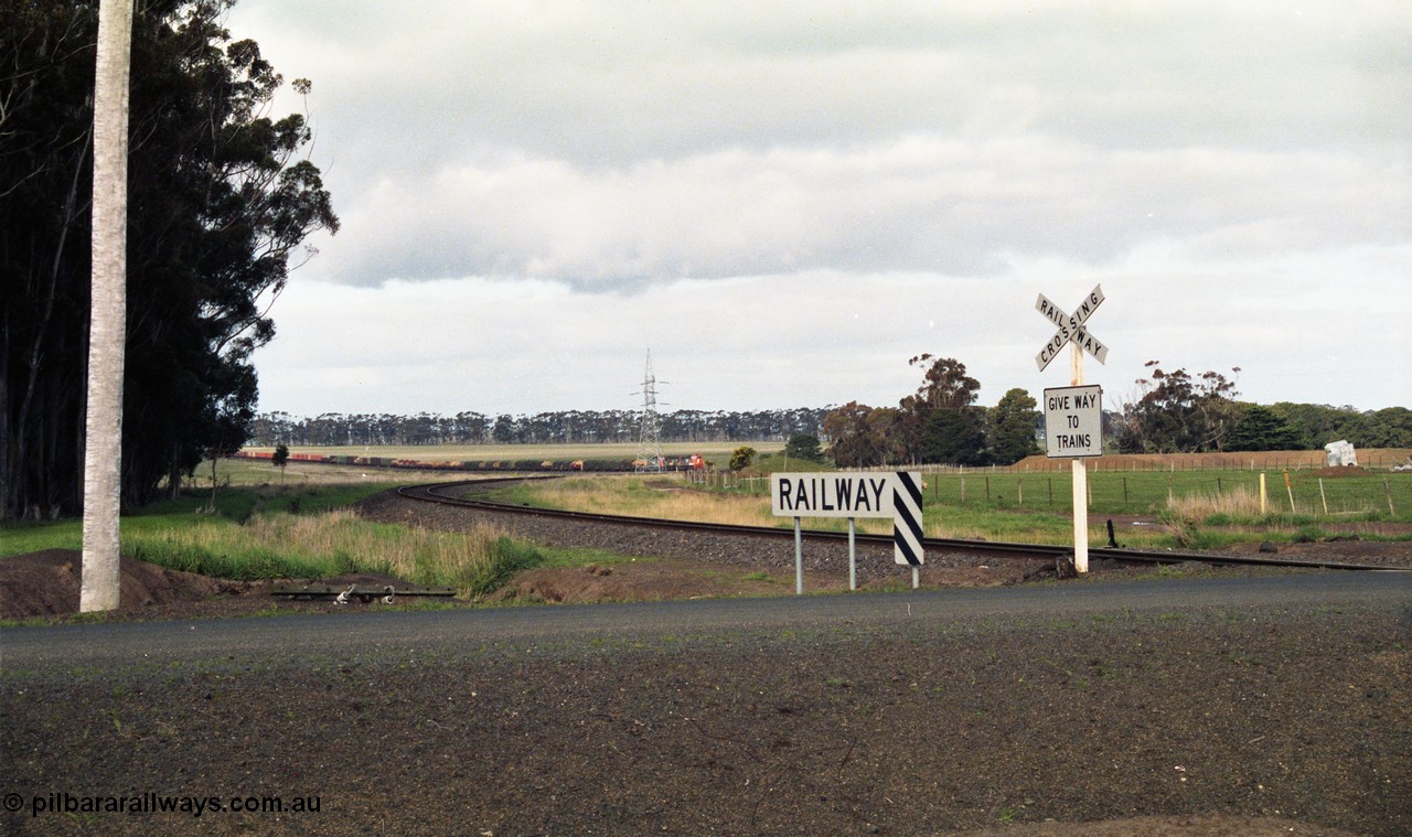 154-08
Lismore, track view looking back towards Geelong, broad gauge goods train 9169 in the valley, taken from Gnarpurt Road crossing.
