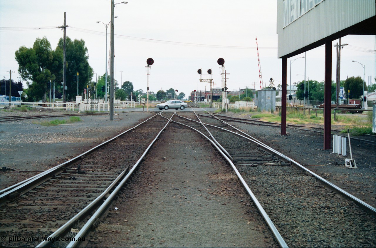 156-07
Shepparton yard view looking north across High Street grade crossing from in-between No.1 and 2 roads, former 'engine track' is on the right, points locked for Tocumwal line on the left, line on the right is to Katamatite, the points on the left of frame are from No.5 Road, searchlight signal posts 10 and 11 are the down home signals for each line, track on the far left cross High Street and is the former SEC Siding, SPC Siding can be seen on the right in the distance.
