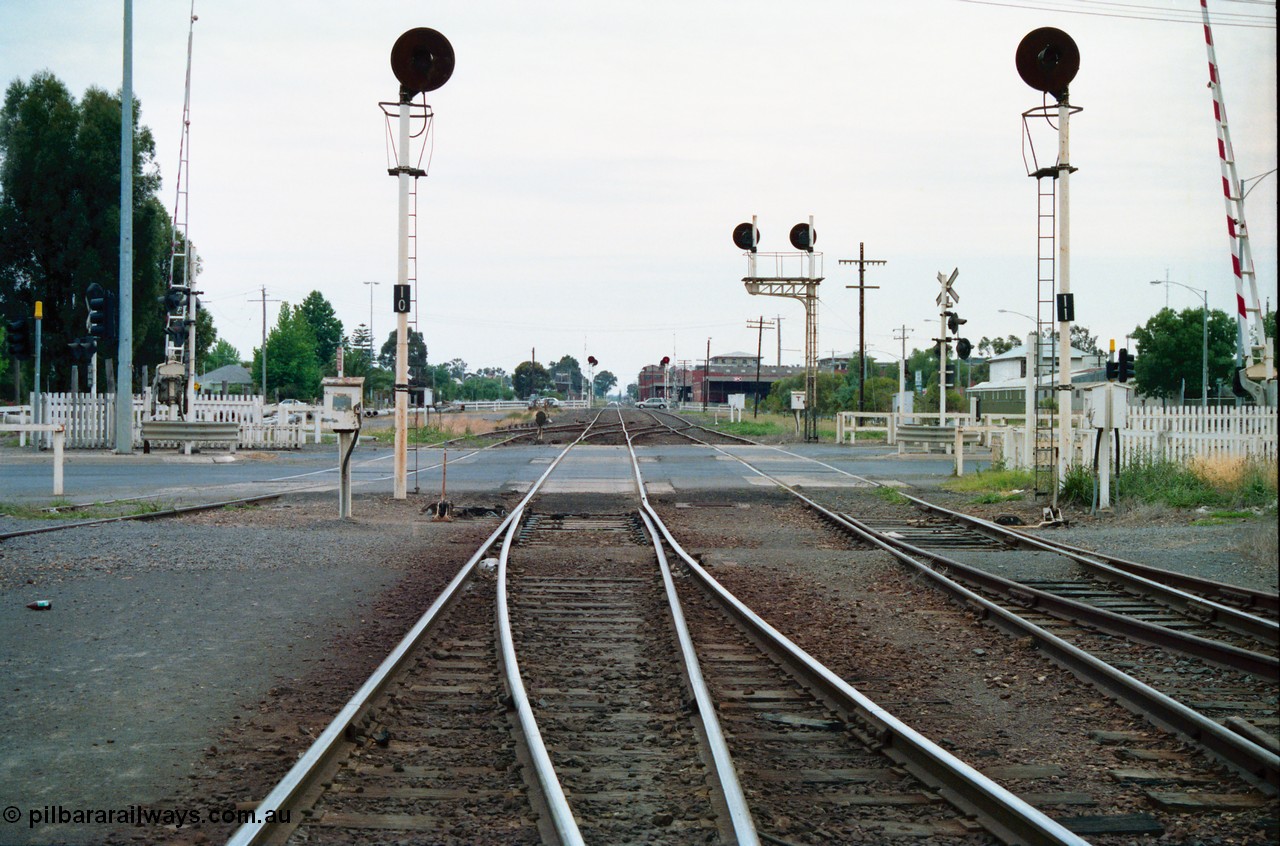 156-09
Shepparton yard view looking north across High Street grade crossing from No.2 Road and the Tocumwal mainline, points for former 'engine track' are on the right, points for the road from the Tocumwal line to No.1 Road set, line on the right is to Katamatite, searchlight signal posts 10 and 11 are the down home signals for each line, track on the far left cross High Street and is the former SEC Siding, SPC Siding can be seen on the right in the distance beyond searchlight signal posts 14 and 15, both down homes.
