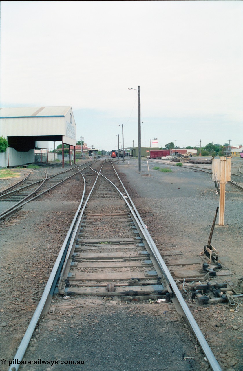 156-12
Shepparton station yard overview, looking south from High Street, mainline points from the Tocumwal line set for No.1 or platform Road, showing point lever, interlocking and telephone cabinet, line on the left is to Katamatite, now Dookie and the former Engine Track heading into the Tubemakers awning, yard roads, goods shed, Freightgate and cement silos in the background right hand side.
