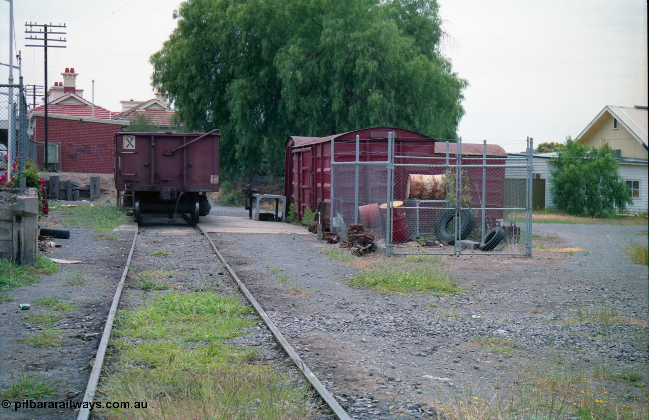 156-17
Shepparton station, former car dock, now Train Examiners Siding, track realigned away from platform, VOCX type bogie open waggon, grounded B vans used as examiners workshop and storage, station building behind.
