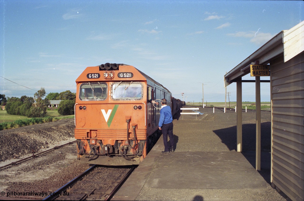 157-04
Gheringhap, view from station platform looking east as V/Line broad gauge G class G 521 Clyde Engineering EMD model JT26C-2SS serial 85-1234 leads down grain train 9121 out of Siding A and receives the electric staff off the signaller for the Ballarat line, safeworking, staff exchange.
Keywords: G-class;G521;Clyde-Engineering-Rosewater-SA;EMD;JT26C-2SS;85-1234;