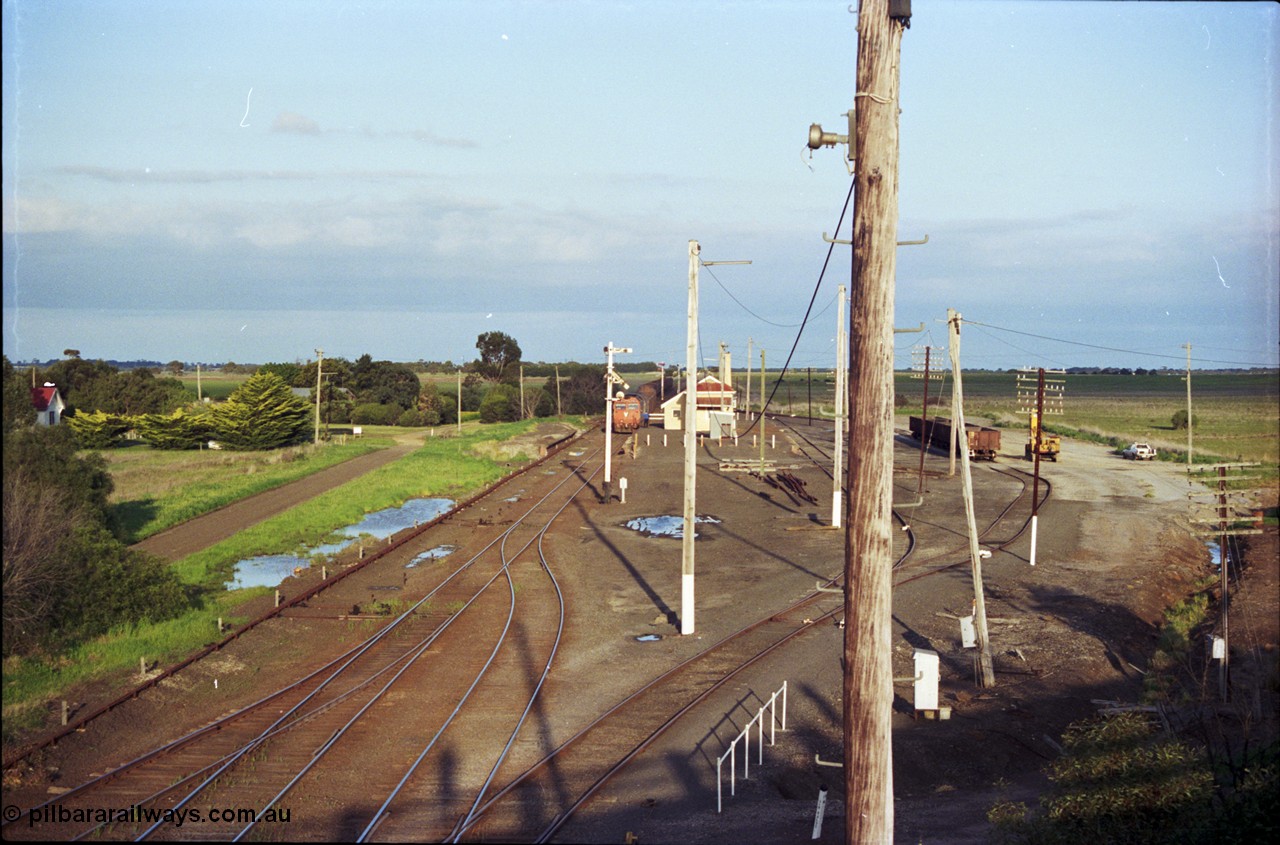 157-05
Gheringhap station yard overview from the Midland Highway overbridge, V/Line broad gauge G class G 530 Clyde Engineering EMD model JT26C-2SS serial 88-1260 leads a sister with down grain train 9123 as it swaps electric staves with the signaller, semaphore signal post 4 is pulled off for the Ballarat line, point rodding and signal wires on the left, the points and Siding C just visible bottom left corner, the Ballarat line continuing straight, while the line to Maroona points off and joins with Sidings B which is used for gypsum traffic, gypsum waggons and unloading contraption at right.
Keywords: G-class;G530;Clyde-Engineering-Somerton-Victoria;EMD;JT26C-2SS;88-1260