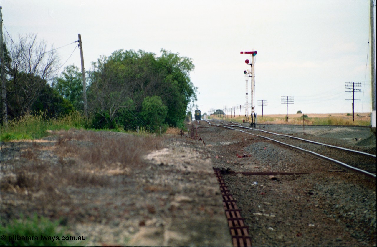 159-09
Gheringhap, track view looking east towards Geelong from the former No.2 platform, signal rodding running along edge of platform, semaphore signal posts and down goods train on approach.
