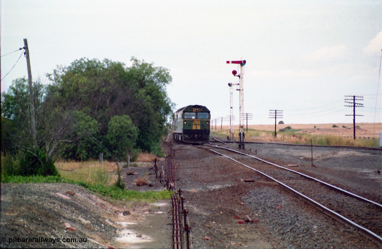 159-10
Gheringhap, track view looking east towards Geelong from the former No.2 platform, signal rodding running along edge of platform, semaphore signal post 3, Australian National broad gauge BL class BL 27 Clyde Engineering EMD model JT26C-2SS serial 83-1011 leads down goods train 9169 as it arrives on their way to Adelaide.
