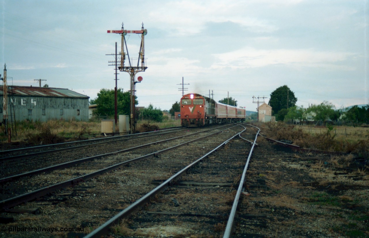 159-15
Ballarat D Signal Box, Linton Junction, broad gauge V/Line N class N 472 'City of Sale' Clyde Engineering EMD model JT22HC-2 serial 87-1201 leads a down Dimboola passenger train with an N set, swings across onto the main western line having got the electric staff for the section to Trawalla, disc signal post 22 for Timken's Siding is just visible at the left, with up home semaphore signal post 23, line in the middle is the Linton Line, taken from the Cattle Yards Line. Semaphore signal post 20 can be seen pulled off for the move in the distance behind the signal box.
Keywords: N-class;N472;Clyde-Engineering-Somerton-Victoria;EMD;JT22HC-2;87-1201;