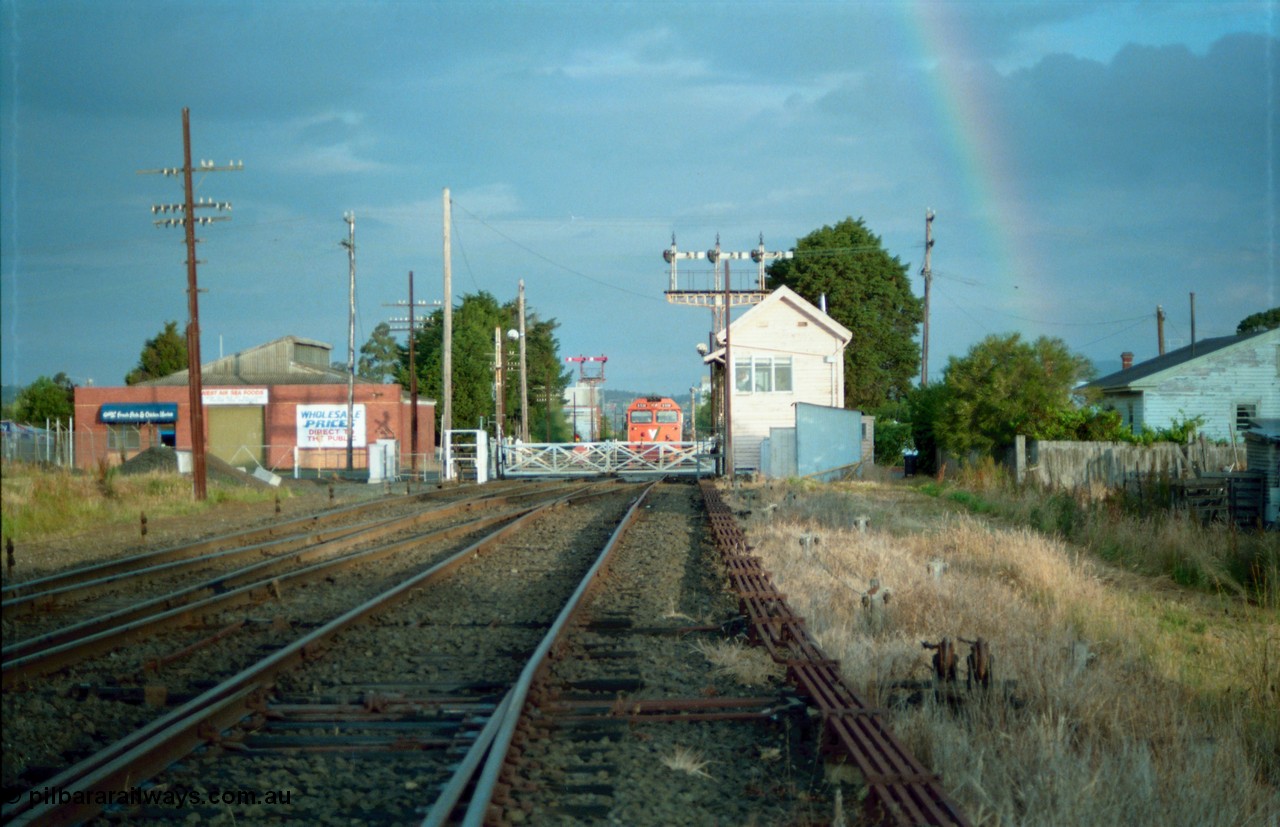 159-19
Ballarat D Signal Box, Linton Junction, broad gauge track view from the points for the Cattle Yard Line looking east, Linton Line then the Ararat Line with the down crossover visible, triple doll semaphore signal 20 facing down trains behind the signal box, with the Gillies Street interlocked gates, staff exchange platform and up home semaphore signal post 19, a V/Line G class awaits line clear to Trawalla with a down goods train stopped just east of Gillies Street gates, points, interlocking, track work and point rodding.
