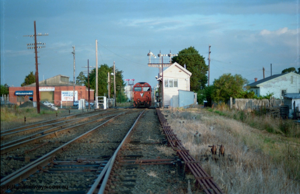 159-20
Ballarat D Signal Box, Linton Junction, with the line now clear, V/Line broad gauge G class G 532 Clyde Engineering EMD model JT26C-2SS serial 88-1262 leads a down Adelaide bound goods train across Gillies Street as the driver receives the electric staff for the section to Trawalla, triple doll semaphore signal post 20 is pulled off for the Ararat line and the interlocked gates are open, points and track work, interlocking and point rodding.
Keywords: G-class;G532;Clyde-Engineering-Somerton-Victoria;EMD;JT26C-2SS;88-1262;