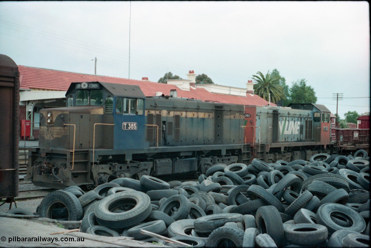 160-24
Shepparton, stabled V/Line broad gauge T class locomotives T 385 Clyde Engineering EMD model G8B serial 64-340 still in Victorian Railways blue and yellow livery and T 393 serial 65-423 off the down Shepparton fuel train, looking from the good loading platform with a mountain of 2nd hand tyres piled up.
Keywords: T-class;T385;Clyde-Engineering-Granville-NSW;EMD;G8B;64-340;