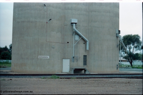 160-31
Tallygaroopna, track view from former station building site looking across tracks to Williamstown style silo complex with train load-out spouts and station name painted on silos.

