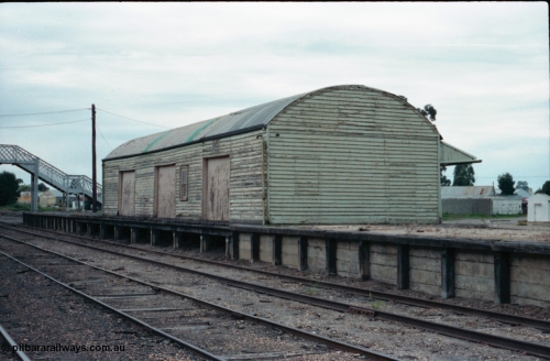 161-04
Numurkah, yard view of goods shed with curved roof and goods loading platform, steel lattice footbridge at end of platform, white build at far right is the road vehicle weighbridge scale room.
