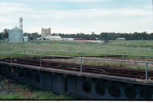 161-32
Tocumwal, overview of the overgrown standard gauge NSWGR yards taken looking south from turntable and pit, silos on the left, derelict flour mill, station building and platform and V/Line broad gauge sleeper transport waggons, standard gauge fettlers shed is at this end of platform.
