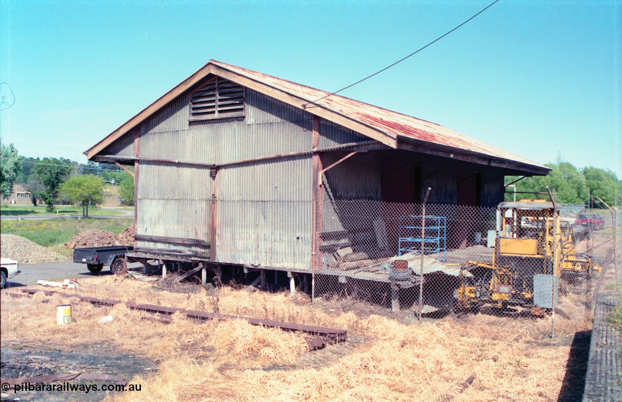 162-1-01
Healesville, view of goods shed, eastern side and loading platform, fenced off compound with track machines, standard Victorian Railways 20 ft goods shed.
