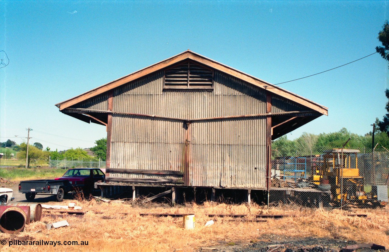 162-1-02
Healesville, view of goods shed, eastern side elevation and loading platform, fenced off compound with track machines, standard Victorian Railways 20 ft goods shed.
